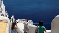 Turis berfoto di Pulau Santorini. Namun, operator kapal pesiar mengatakan pungutan itu tidak adil. George Koumpenas, Chief Operating Officer untuk Celestyal, yang menyelenggarakan perjalanan ke pulau-pulau Yunani, mengatakan bahwa pungutan itu hanya menyasar kapal pesiar dan itu untuk pengumpulan pajak dan tidak akan membantu mengatasi kelebihan turis. Foto: REUTERS/Louiza Vradi