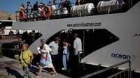 Turis turun dari kapal pesiar di Pulau Santorini. Pajak baru ini untuk mencoba mengendalikan kelebihan turis dan mengumpulkan pendapatan guna meningkatkan infrastruktur pulau tersebut. Foto: REUTERS/Louiza Vradi