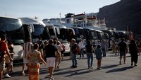 Penumpang kapal pesiar MSC memasuki bus di Pulau Santorini. Pemerintah Yunani akan mulai memungut biaya masuk sebesar 20 euro bagi setiap penumpang pada tanggal 21 Juli. Biaya tersebut akan menjadi 12 euro pada bulan Oktober dan turun menjadi 4 euro dari bulan November hingga Maret, naik lagi menjadi 12 euro dari bulan April hingga Mei mendatang. Foto: REUTERS/Louiza Vradi