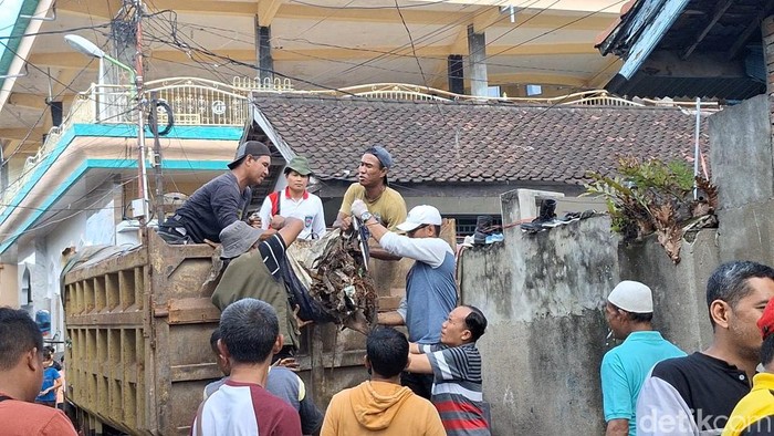 Wali Kota Mataram Mohan Roliskana bersama warga mengangkut sampah sisa banjir di Lingkungan Karang Kemong, Cakranegara, Kota Mataram, Rabu (9/7/2025). (Foto: Nathea Citra/detikBali)