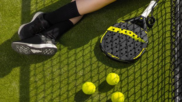 Close-up photo. Padel tennis player with racket. Girl athlete with paddle racket on court outdoors. Sport concept. Download a high quality photo for the design of a sports app or web site.