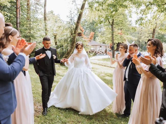 full-length portrait of the newlyweds and their friends at the wedding. The bride and groom with bridesmaids and friends of the groom are having fun and rejoicing at the wedding.