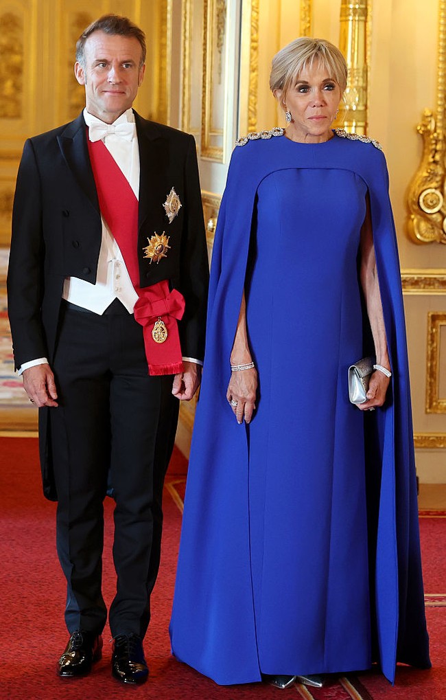Brigitte Macron yang belum lama ini berkunjung ke Indonesia juga hadir dalam balutan gaun serupa. Busana berbahan silk crepe tersebut disiapkan khusus oleh Louis Vuitton. Pada bagian pundak, diberi aksentuasi berbentuk kancing berlian yang diaplikasikan dengan teknik hand-embroidery.  (Foto: Chris Jackson/Getty Images)