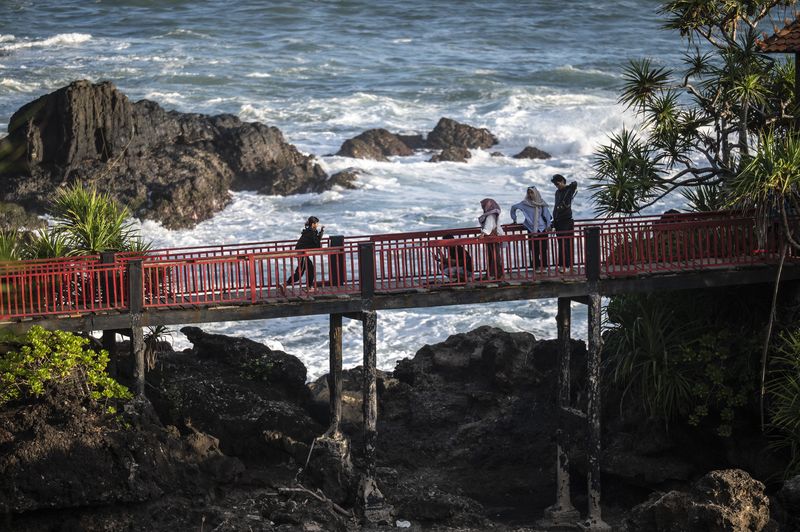 Wisatawan berdiri sambil memotret di bebatuan karst kawasan geosite Pantai Menganti, Desa Karangduwur, Kecamatan Ayah, Kabupaten Kebumen, Jawa Tengah, Rabu (9/7/2025). Pantai Menganti merupakan salah satu geosite di kawasan Geopark Kebumen yang resmi diakui sebagai UNESCO Global Geopark pada April 2025 dengan keistimewaan pantainya terletak pada keberadaan bebatuan columnar joint (struktur basalt kolumnar) yang menandakan proses pendinginan lava kuno di tebing pantai. ANTARA FOTO/Aprillio Akbar/tom.