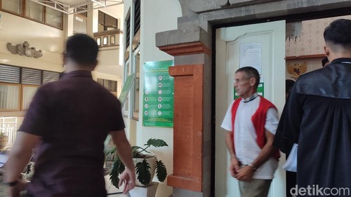 Pensiunan militer Amerika Serikat, Brant Robert Joyce (56) keluar ruang sidang Pengadilan Negeri (PN) Denpasar, Kamis (10/7/2025).