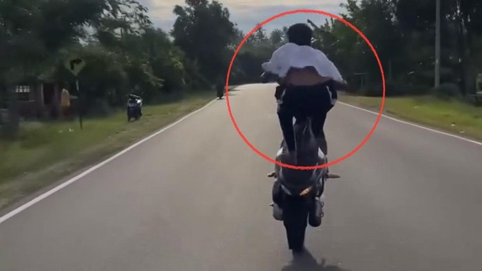 Seorang remaja melakukan freestyle motor di jalan raya depan Polsek Duampanua.