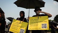Aktivis membawa poster aspirasi dan payung saat mengikuti Aksi Kamisan ke-868 di depan Istana Merdeka, Jakarta. Barisan aktivis tetap berdiri diam dalam sunyi di tengah panas Jakarta, simbol konsistensi perjuangan mereka untuk hak asasi dan kejujuran sejarah bangsa. Foto: ANTARA FOTO/Sulthony Hasanuddin