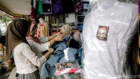 Seorang ibu bersama anaknya mencoba memilih rok sekolah di salah satu kios perlengkapan sekolah. Menjelang tahun ajaran baru 2025/2026 penjualan berbagai jenis perlengkapan sekolah seperti baju seragam, tas, dan sepatu mengalami peningkatan dibandingkan dengan hari biasa.