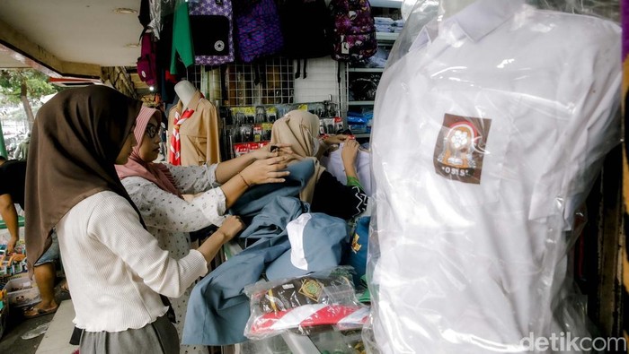 Orang tua bersama sang anak  memilih dan mencoba peralatan sekolah di kios perlengkapan sekolah di Pasar Kebayoran Lama, Jakarta, Jumat (11/7/2023). Menjelang tahun ajaran baru 2025/2026 penjualan berbagai jenis perlengkapan sekolah seperti baju seragam, tas, dan sepatu mengalami peningkatan dibandingkan dengan hari biasa.