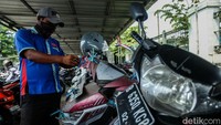 Petugas memasang tali plastik di sepeda motor Yamaha Xeon yang telah terparkir selama empat tahun.