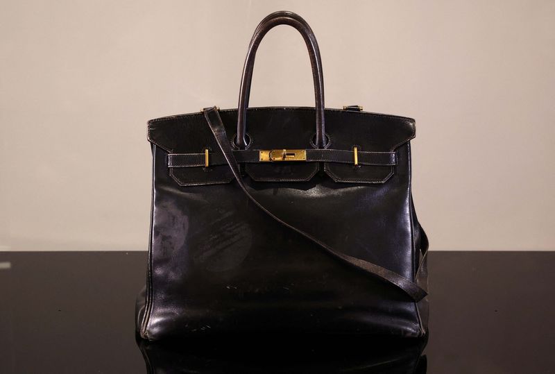 A cameraman films the Original Birkin, the handbag crafted by French luxury fashion house Hermes for artist Jane Birkin and offered to her in 1985, displayed during a media preview of Sotheby's Paris Fashion Icons Sale at Sotheby's auction house in Paris, France, July 2, 2025. REUTERS/Tom Nicholson