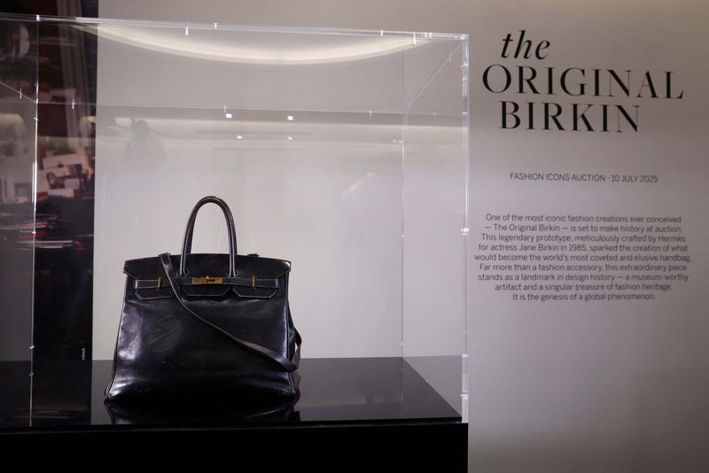 A cameraman films the Original Birkin, the handbag crafted by French luxury fashion house Hermes for artist Jane Birkin and offered to her in 1985, displayed during a media preview of Sotheby's Paris Fashion Icons Sale at Sotheby's auction house in Paris, France, July 2, 2025. REUTERS/Tom Nicholson