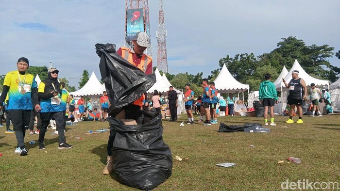 Di balik kesuksesan lari ribuan peserta, ada Pasukan Oranye yang sigap memastikan area lintasan dan sekitarnya tetap bersih dari sampah. (Mei Amelia/detikcom).