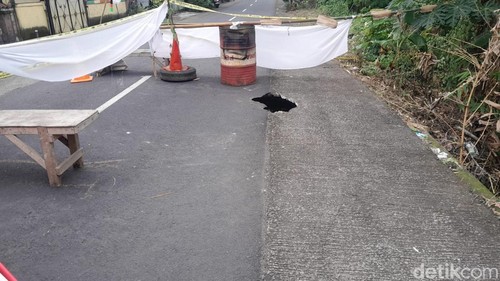 Jalan jebol di Desa Tista, Kecamatan Kerambitan, Tabanan mengakibatkan arus tersendat dan dialihkan, Minggu (13/7/2025). (Krisna Pradipta)