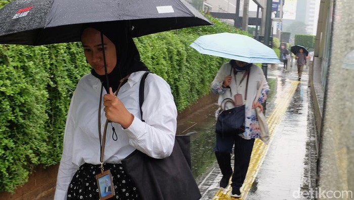 Warga menggunakan payung menerobos gerimis di pelican crossing Jl Thamrin, Jakarta, Senin (14/7/2025). Curah hujan terpantau masih tinggi meskipun sudah memasuki musim kemarau. Berdasarkan prediksi curah hujan bulanan Badan Meteorologi, Klimatologi, dan Geofisika (BMKG), anomali curah hujan di atas normal berlangsung sejak Mei hingga Oktober 2025.  BMKG memprediksi bahwa kemarau 2025 akan mengalami keterlambatan di sekitar 29 persen Zona Musim (ZOM), terutama di wilayah Lampung, sebagian besar Pulau Jawa, Bali, Nusa Tenggara Barat (NTB), dan Nusa Tenggara Timur (NTT).