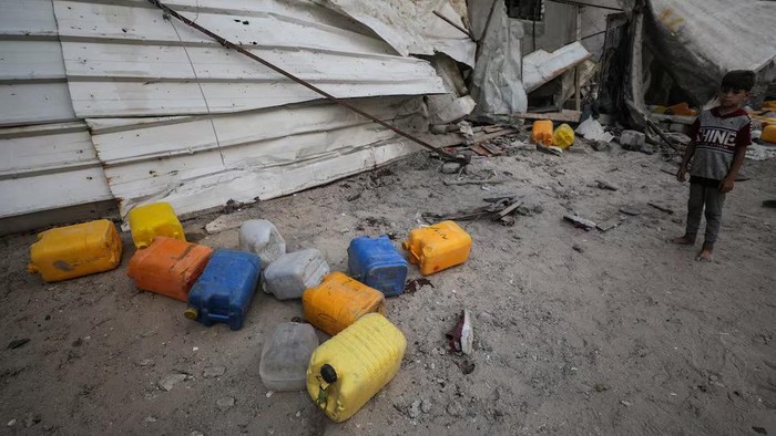 A Palestinian boy inspects the site of an Israeli strike that killed Palestinians, gathered to collect water from a distribution point, according to medics, in Nuseirat in the central Gaza Strip July 13, 2025. REUTERS/Stringer Purchase Licensing Rights
