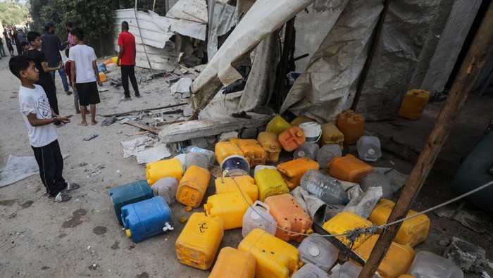 People inspect the site of an Israeli strike that killed Palestinians, gathered to collect water from a distribution point, according to medics, in Nuseirat in the central Gaza Strip July 13, 2025. REUTERS/Stringer