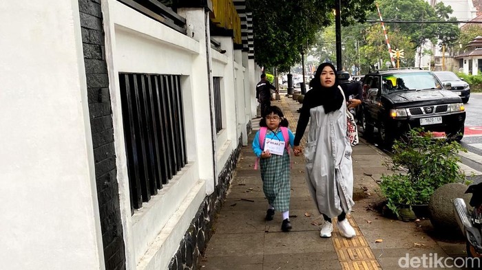Orang tua mengantar anaknya menuju sekolah hari pertama di SDN 0001 Merdeka Bandung.