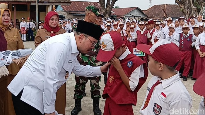 Tangis Rizki Apriadi (12) siswa baru SMPN 47 Palembang saat diberikan seragam gratis
