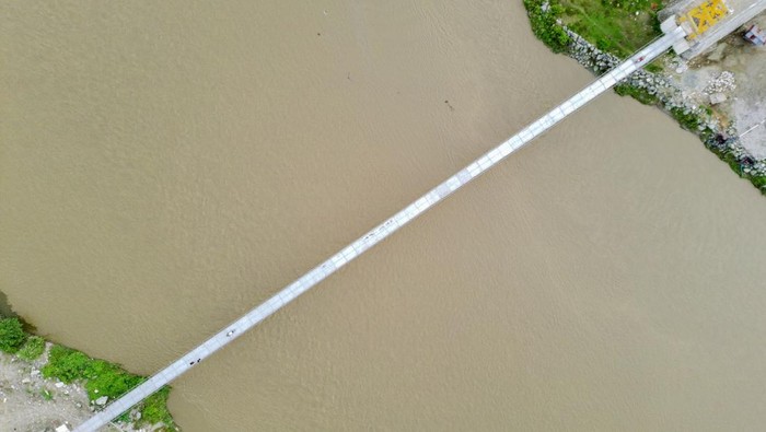 Dua Kali Ambruk, Jembatan Gantung Akses Vital Warga Sigi Kembali Difungsikan Pengendara sepeda motor dan pejalan kaki melintas di atas jembatan gantung yang baru dioperasikan di Desa Tinggede, Sigi, Sulawesi Tengah, Selasa (15/7/2025). Setelah dua kali ambruk akibat bencana pada 2015 silam, jembatan gantung dengan bentangan 115 meter yang menghubungkan Desa Tinggede dan Desa Kalukubula di Kabupaten Sigi dan hanya dapat dilewati pejalan kaki dan sepeda motor itu akhirnya difungsikan untuk umum setelah direkonstruksi. ANTARA FOTO/Basri Marzuki/bar