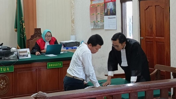 I Made Kertha saat berkoordinasi dengan penasihat hukumnya, Muh Lukman Hakim, dalam persidangan di PN Denpasar, Selasa (15/7/2025). (Ahmad Firizqi Irwan/detikBali)