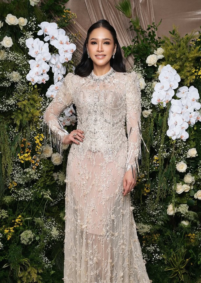 Penampilan Maia kian elegan dengan dress dari Maison Baaz Couture. Long dress bernuansa nude itu memiliki sentuhan glamor dengan berhias penuh payet, manik-manik, serta bordir. Terdapat elemen tassel atau rumbai panjang pada bagian lengan, menambah kesan dramatis dan mewah. Foto: Instagram/@deanmua_
