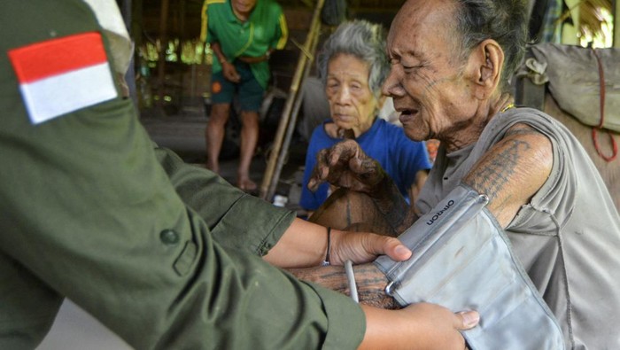 Bidan Ilen memeriksa kondisi kesehatan seorang Sikerei (dukun Mentawai) yang sakit di rumah di Dusun Matektek, Desa Matotonan, Siberut Selatan, Mentawai, Sumatera Barat.