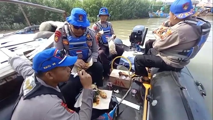 Momen anggota Polair Pemalang menyantap makanan yang diberi emak-emak saat amankan sedekah laut di Comal, Senin (14/7/2025).