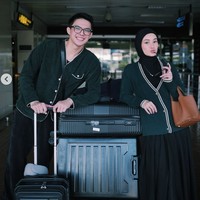 Dinda dan Rey tampil serasi di bandara dengan outfit travel bernuansa hitam dan hijau tua. Mereka mengenakan jaket matching dan membawa koper besar. Foto: Instagram/@rey_mbayang