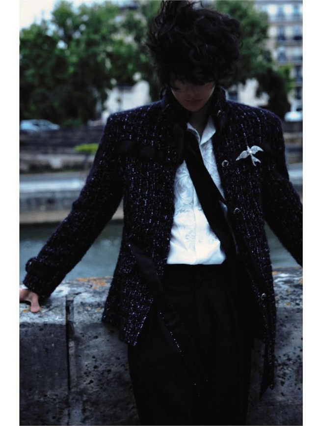 Aksen pita hitam yang menjuntai di sisi jaket menambahkan sentuhan chic, sementara bros berbentuk serangga berwarna perak statement elegan—ikonik dalam gaya Chanel. Foto: Instagram/@yibo.w_85