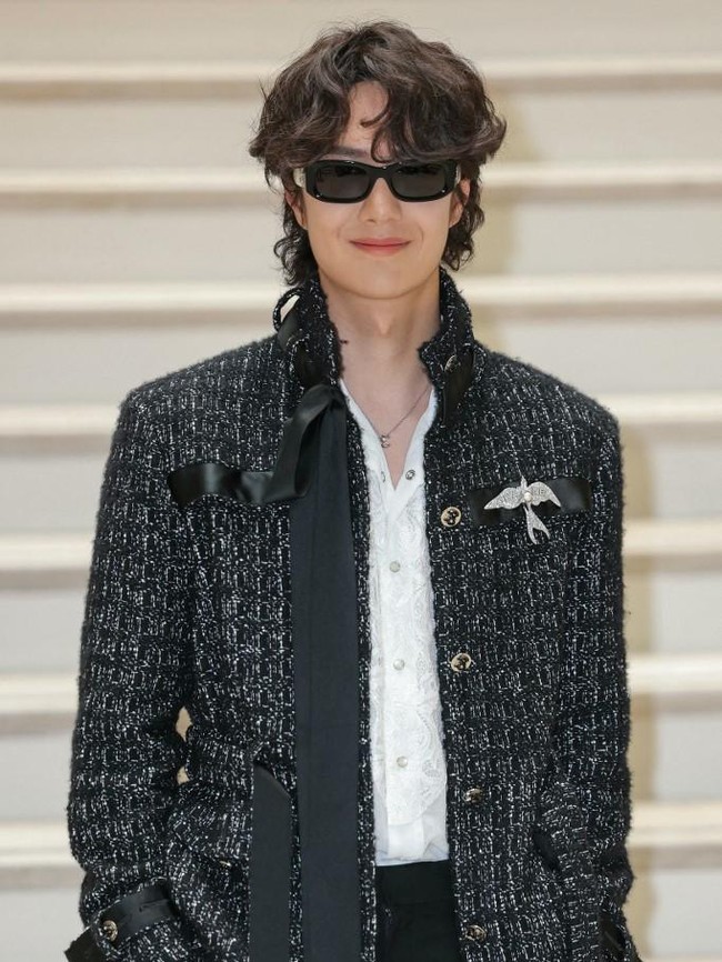 Wang Yibo tampak memegang clutch berbentuk box dengan handle putih yang kontras, menciptakan vibe edgy yang kontemporer. Foto: Thomas SAMSON / AFP