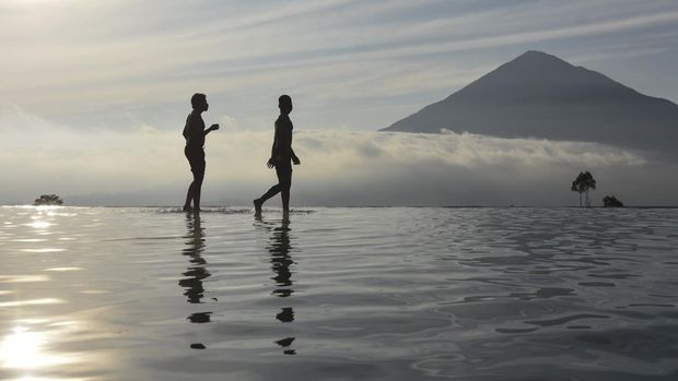 Pengunjung berenang di kolam renang air hangat alami saat menikmati sunrise Gunung Cikuray di Agrowisata Tepas Papandayan, Desa Karamatwangi, Kecamatan Cisurupan, Kabupaten Garut, Jawa Barat, Rabu (16/7/2025). Agrowisata Tepas Papandayan yang dibangun pada tahun 2019, oleh Pemerintah Desa dan dikelola Badan Usaha Milik Desa (BUMDes) Keramat Jaya itu, mendapatkan omset Pendapatan Asli Desa (PAD) sebesar Rp100 juta-Rp150 juta per tahun. ANTARA FOTO/Adeng Bustomi/foc.