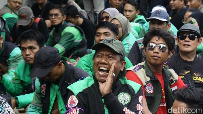 Ratusan ojol gelar demo di Monas, Kamis (17/7), menolak status buruh dan potongan 10%, serta mendesak Perppu sebagai payung hukum layanan ojol.