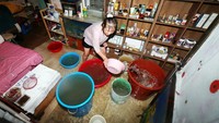 Seorang wanita membersihkan lantai salon rambutnya yang kebanjiran akibat hujan deras di Gwangju, Korea Selatan, Kamis (17/7/2025). Toko dan unit usaha lokal terendam saat hujan ekstrem mengguyur dan memperburuk krisis air dan infrastruktur. (Yonhap via REUTERS)  