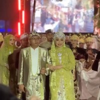 Di acara resepsi Maulana mengenakan beskap berwarna gold muda dengan kain batik motif parang dan flora sebagai bawahannya. Kepala mempelai pria dihiasi blangkon batik. Sementara Putri tampil dengan kebaya modern bernuansa hijau keemasan lengkap dengan Siger di kepalanya. Foto: Instagram/@putri.karlina14