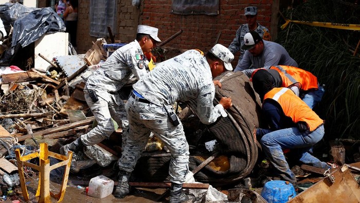 A woman works to remove debris caused by flooding in the aftermath of heavy rains, in Zapopan, Mexico, July 16, 2025. REUTERS/Michelle Freyria
