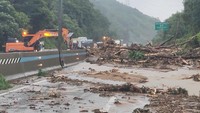 Foto saksi mata pada hari Kamis (17/7) menunjukkan petugas tanggap darurat bekerja membersihkan jalan raya dari dahan pohon tumbang yang menghalangi jalan, setelah Korea Selatan dilanda hujan deras. Foto: Park Jin Dong/via REUTERS