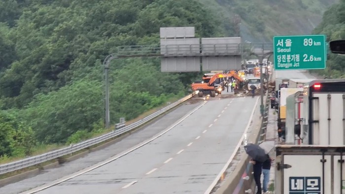 Emergency personnel in excavators clear a highway of fallen tree branches and soil after a landslide, in the aftermath of torrential rain, in Dangjin, South Korea, July 17, 2025, in this still image obtained from a social media video. Park Jin Dong/via REUTERS  THIS IMAGE HAS BEEN SUPPLIED BY A THIRD PARTY. MANDATORY CREDIT.