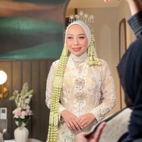 Penampilannya kian lengkap dengan hijab serasi dengan kebaya, dan dipercantik dengan sanggul ronce melati yang menjuntai panjang di kedua sisi. Juga terdapat bros besar di dada yang menambah kesan tradisional dan berkelas. Foto: Instagram/@putri.karlina14