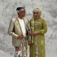 Di acara resepsi Maulana mengenakan beskap berwarna gold muda dengan kain batik motif parang dan flora sebagai bawahannya. Kepala mempelai pria dihiasi blangkon batik, pelengkap penampilan keseluruhan yang memperkuat nuansa budaya. Foto: Instagram/@putri.karlina14