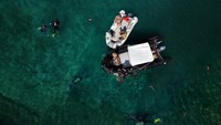 Tim dari Swiss dan Albania ini menghabiskan berjam-jam setiap hari sekitar tiga meter (9,8 kaki) di bawah air, dengan tekun mengambil panggung kayu yang menopang rumah-rumah. Foto: REUTERS/Fatos Bytyci
