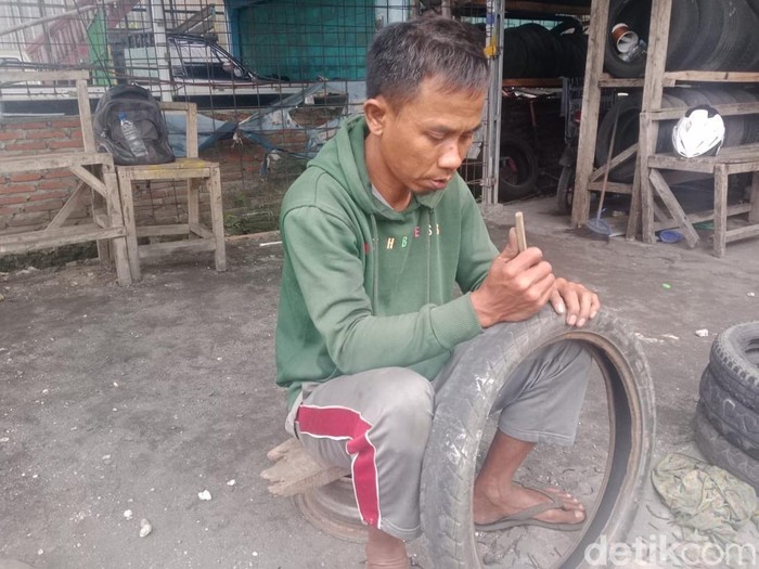 Yanto sedang memodifikasi ban sepeda motor bekas yang bisa layak dipakai