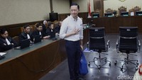 Tom mengenakan kemeja berwarna putih. Tom hanya tersenyum jelang sidang. Dia juga mengatupkan tangannya.