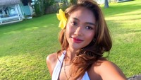 Marion Jola mengunggah momen saat menikmati cahaya sinar matahari di pinggir pantai. Dia duduk di hamparan rumput hijau yang berada di halaman sebuah rumah pantai. Foto: dok. Instagram Marion Jola