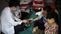 Petugas kesehatan memeriksa seorang perempuan lansia yang berada di tempat pengungsian. REUTERS/Kim Hong-Ji