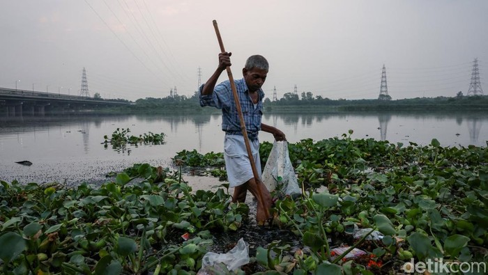 Ramu Gupta, a 67-year-old man who goes to the river to hunt for coins and other valuables, pulls out a bag filled with plastic from the waters of river Yamuna in New Delhi, India, June 26, 2025. REUTERS/Bhawika Chhabra