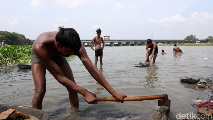 Ramu Gupta, a 67-year-old man who goes to the river to hunt for coins and other valuables, pulls out a bag filled with plastic from the waters of river Yamuna in New Delhi, India, June 26, 2025. REUTERS/Bhawika Chhabra