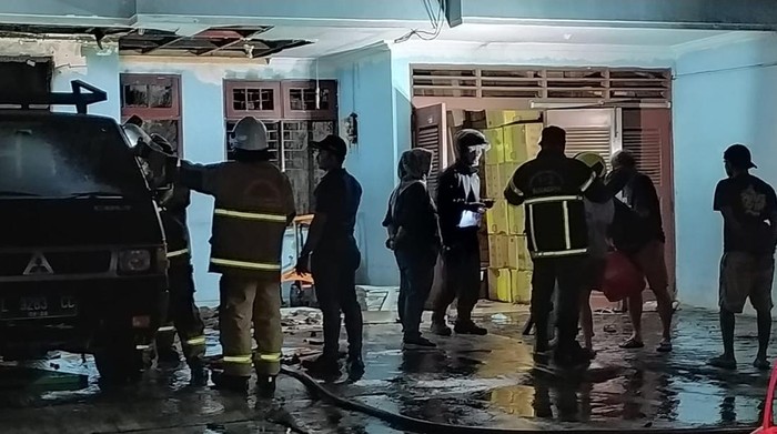 Petugas melakukan pembasahan di rumah di Jalan Wonoayu, Kecamatan Rungkut, Surabaya yang terbakar