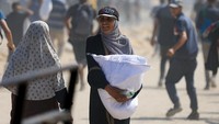 Di tengah kondisi yang serba terbatas, warga terlihat membawa karung-karung bantuan dengan penuh perjuangan. REUTERS/Dawoud Abu Alkas