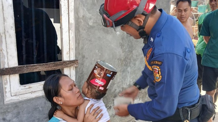 Petugas damkar saat membantu melepaskan kaleng biskuit di kepala bocah di Bandar Lampung.